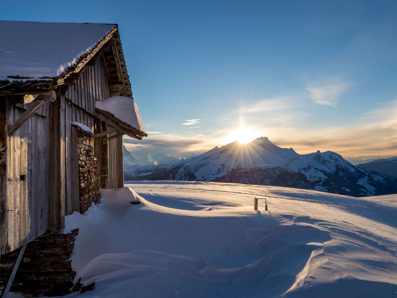 Im Sonnenuntergang - und vor eindrücklicher Bergkulisse: Zwei Schneeschuhläufer*innen unterwegs am Hasliberg