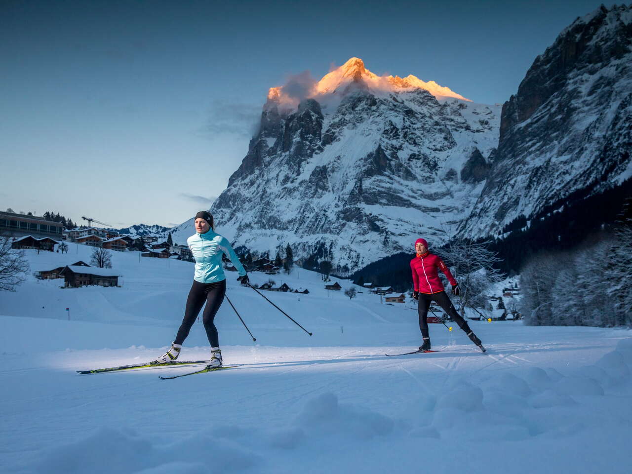 Langlaufloipe Grindelwald Grund. Die zwei Langläuferinnen geniessen die allerletzten Sonnenstralen.