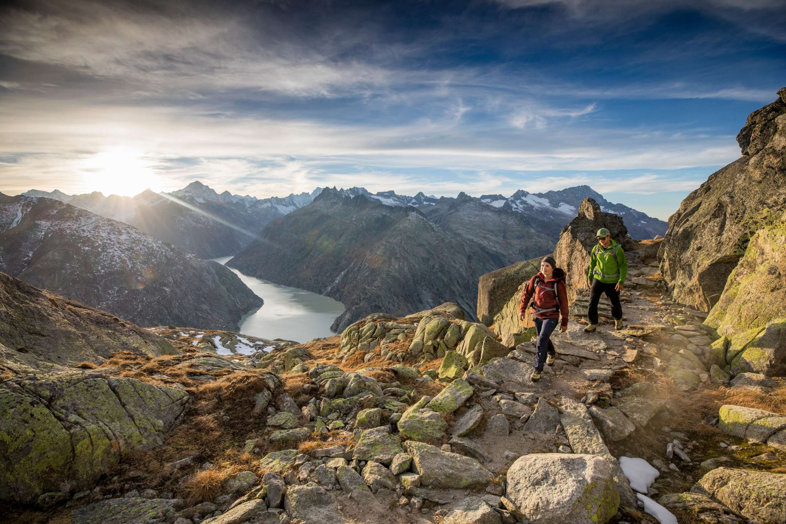 Wandern Grimselwelt Zwei Wanderer unterwegs in der Grimselwelt. Sie wandern vor einmaliger Aussicht auf einen Stausee der Grimselwelt.