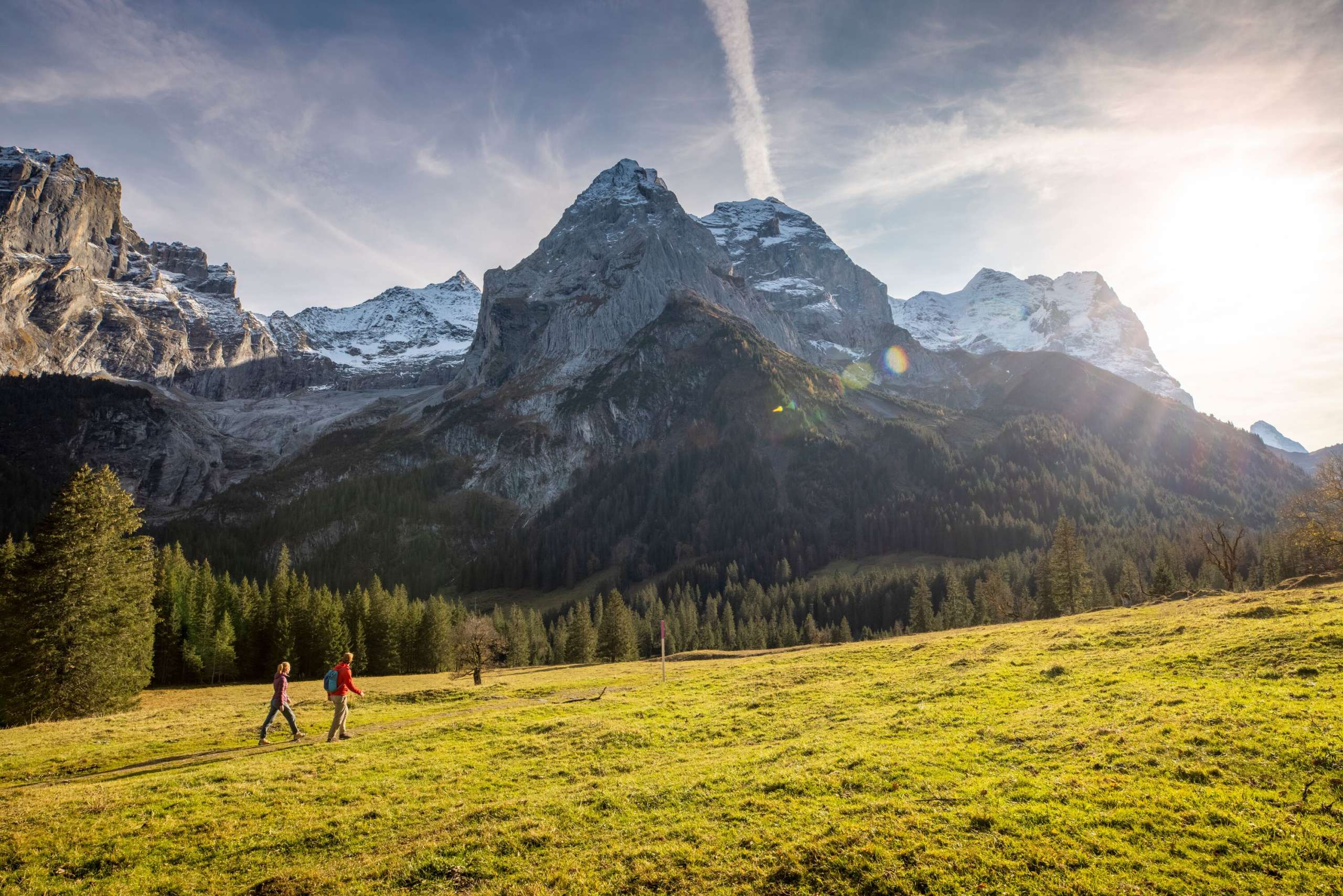 Herbstwanderung über eine Lichtung. Die Wanderer schauen sich das Bergpanorama im Rosenlauital mit den leicht verschneiten Gipfeln an.