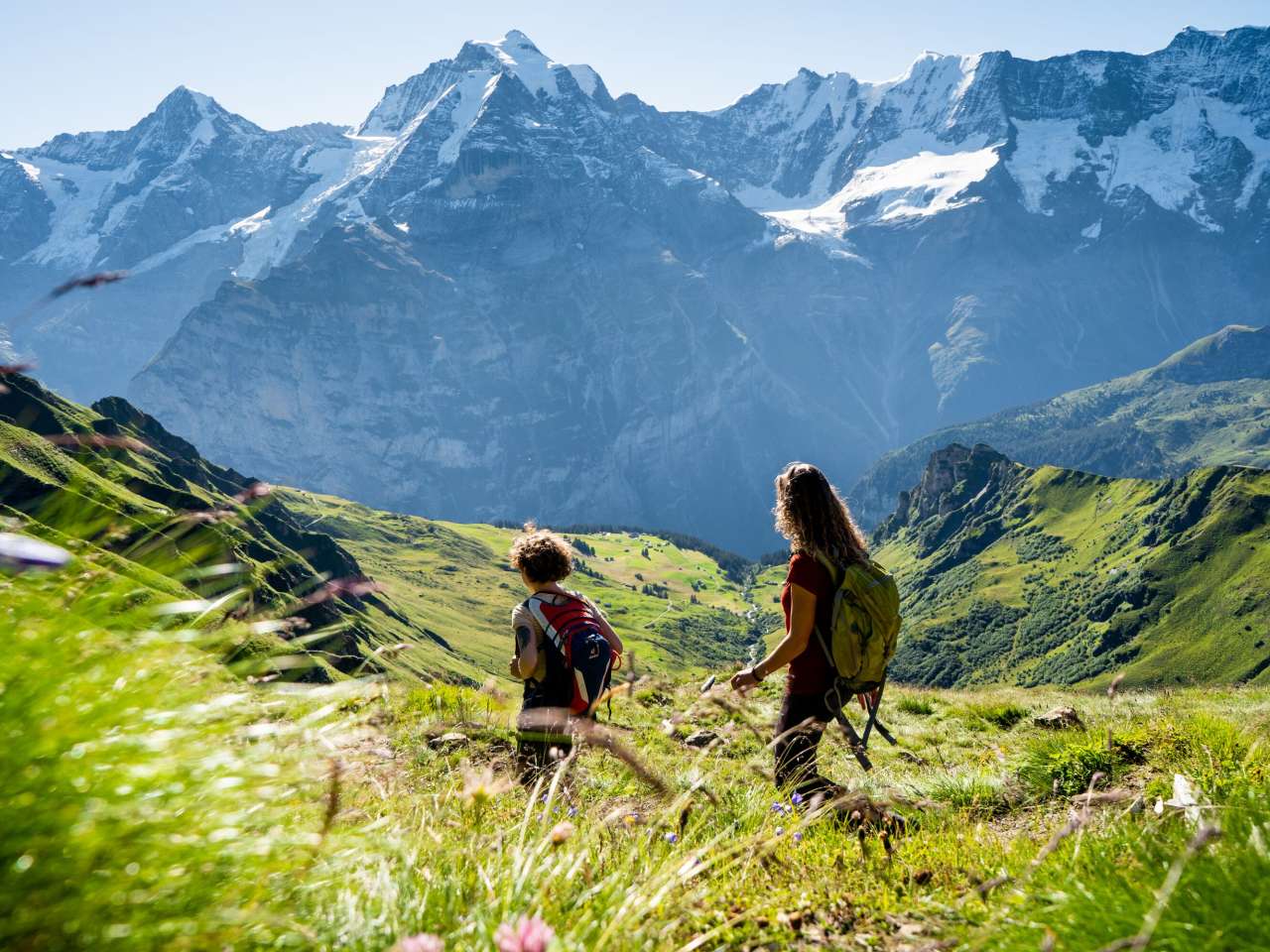 Wandern im Blumental in Mürren Zwei Freundinnen wandern im Blumental in Mürren. Sie geniessen den Ausblick über die grüne Landschaft mit dem weissen Bergpanorama mit Eiger, Mönch und Jungfrau im Hintergrund.