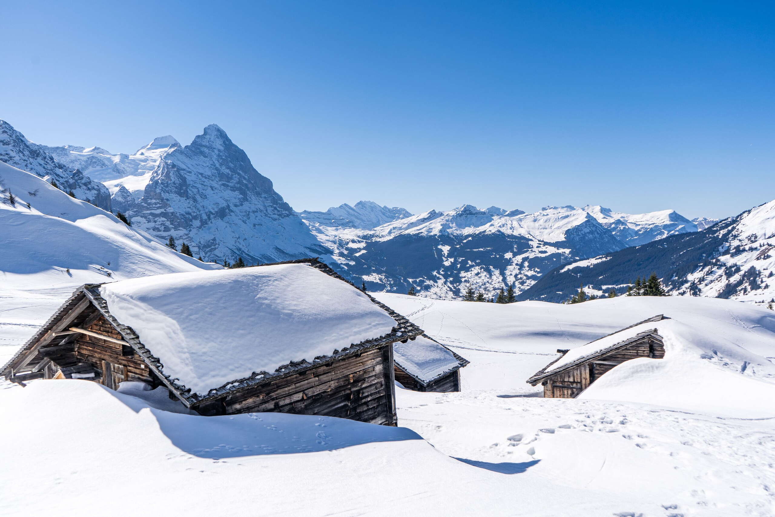 Verschneite Alphütten inmitten des imposanten Bergpanoramas ob Grindelwald.