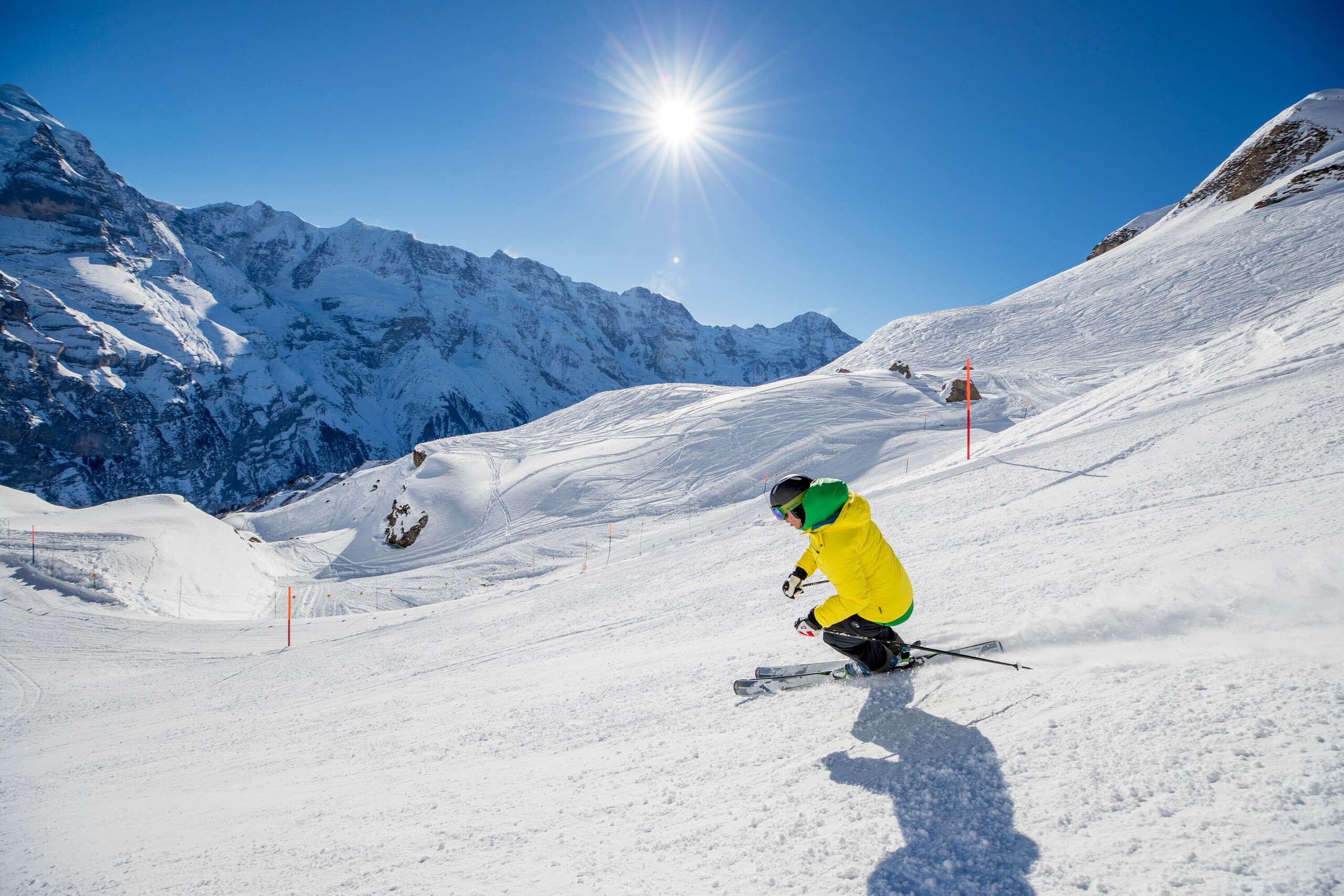 Ein Skifahrer zieht auf der Piste im Skigebiet Mürren-Schilthorn seine Kurven. Ein verschneites Bergpanorama ist im Hintergrund zu sehen.