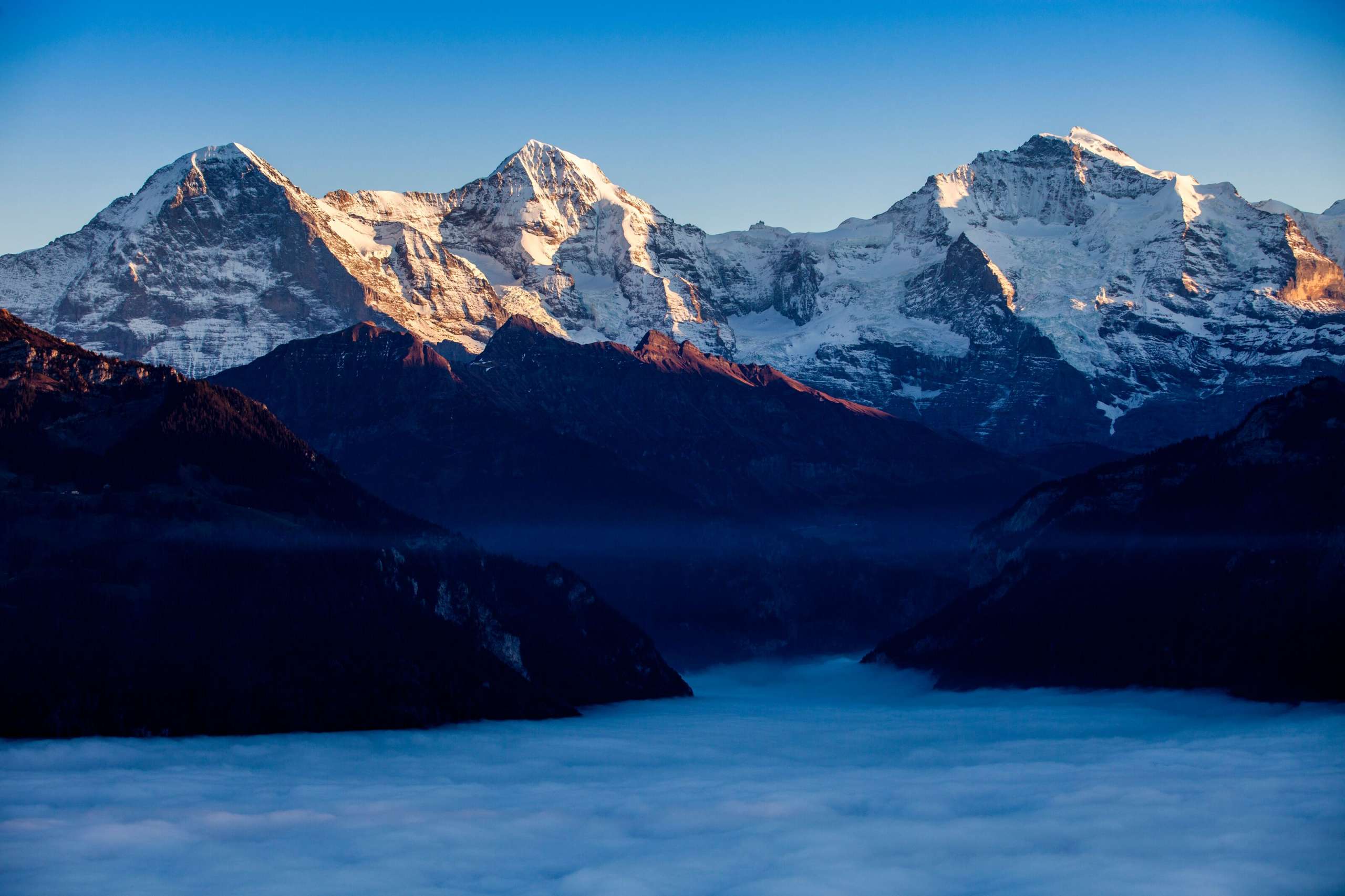 Das weltberühmte Dreigestirn Eiger, Mönch und Jungfrau in der Dämmerung über dem Nebelmeer.